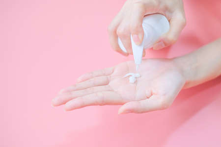 Woman applying moisturizing hand cream on hand with pink background, Health care concept.の写真素材