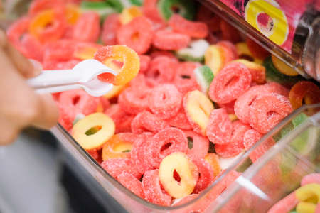 Woman grabbing colorful jelly, colorful background concept.