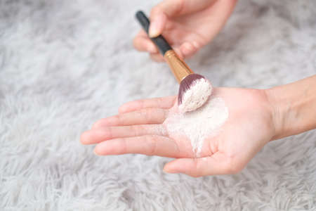 Close up woman holding talc make up and brush on carpet background, beauty concept.の写真素材