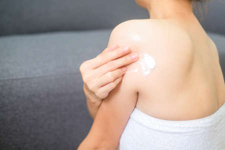 Woman applying cream and lotion on back, treatment and cosmetic and cleaning.の写真素材