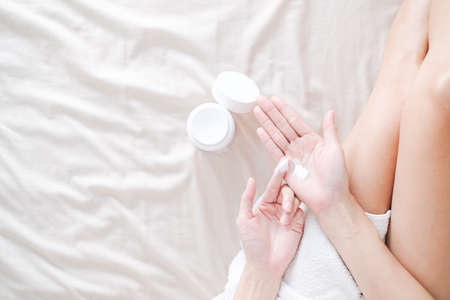 Woman applying natural cream on bed, Woman moisturizing her hand with cosmetic cream, Spa and Manicure concept.の写真素材