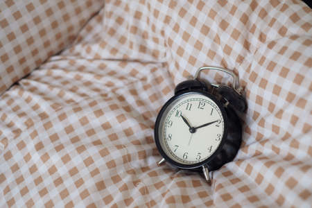 Black alarm clock and bed decoration in bedroom. Close Up view. copy space for design.の写真素材