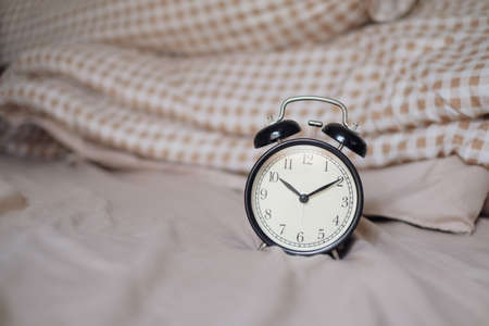 Black alarm clock and bed decoration in bedroom. Close Up view. copy space for design.の写真素材