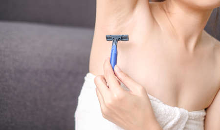 Woman shaving armpit with razor on black background.の写真素材