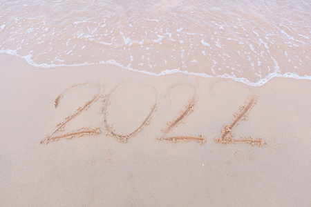 Message Year 2022 replaced by 2023 written on beach sand background. Good bye 2022 hello to 2023...