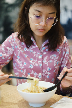 Woman eating noodle in restuarant.