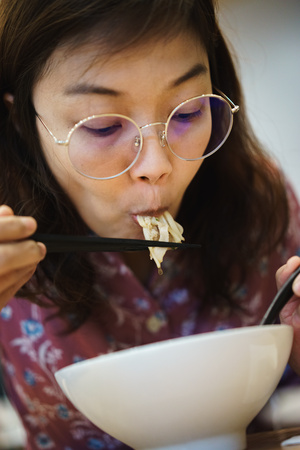 Woman eating noodle in restuarant.の写真素材