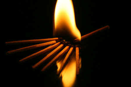 Flaming matches lighting in the dark with reflections on the floor
