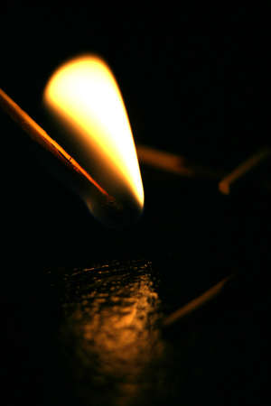 flaming matches lighting in the dark with reflections on the floorの写真素材