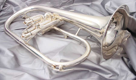 Silver fluegelhorn with mouthpiece on a silver fabricの写真素材