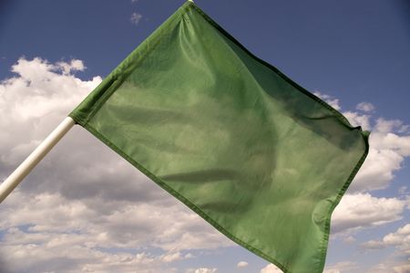 Green flag on a background of the dark blue sky with clouds.の写真素材