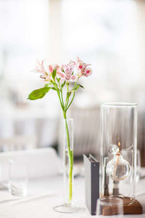 Lilly flower in a vase on a covered tableの写真素材