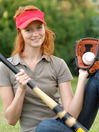Baseball girl holding bat and ball in mittの写真素材
