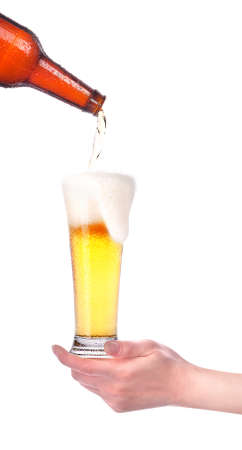 beer pouring from bottle in to the glass with hand isolatedの写真素材