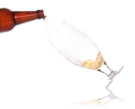 beer pouring from bottle in to the glass isolated on a white backgroundの写真素材