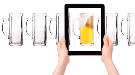 empty and one full beer on tablet computer screen  isolated on a white backgroundの写真素材