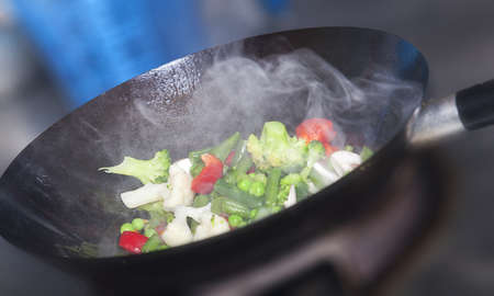 Wok cooking healthy asian food with vegetables and mushroomsの写真素材