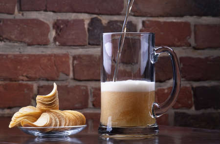 background with glass of Fresh Beer and plate full of chipsの写真素材