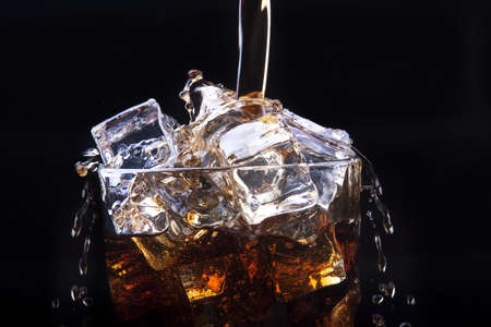 Fresh cola drink background with ice and splash on a blackの写真素材