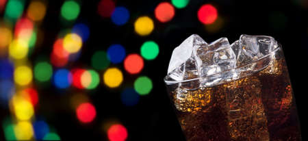 party background with fresh splashing cola full of ice cubes on a blackの写真素材