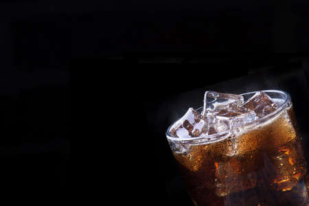 Fresh cola drink background with ice and splash on a blackの写真素材