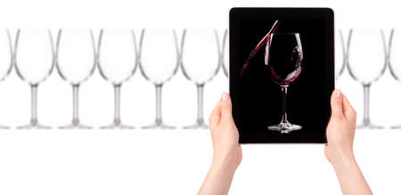 glass of red wine on tablet computer screen isolated on a white backgroundの写真素材