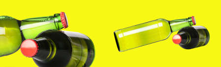 green beer bottles with red caps isolated on a yellow backgroundの写真素材