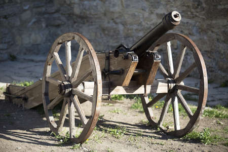 Old medieval artillery canon before a brick wallの写真素材