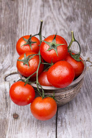 Cherry tomatoes on wooden table with water dropsの写真素材