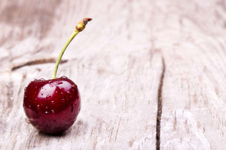Cherries on wooden table with water drops macro backgroundの写真素材