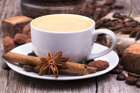 white cup of espresso full of coffee roasted beans with plate on a wooden tableの写真素材