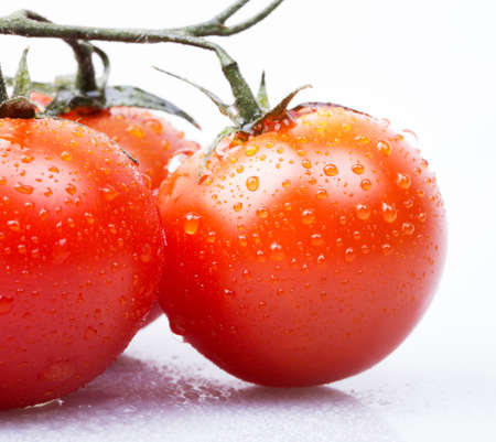 cherry tomatoes on a white macro background with water dropsの写真素材