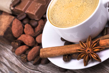 white cup of espresso full of coffee with Chocolate bar and spices on wooden tableの写真素材