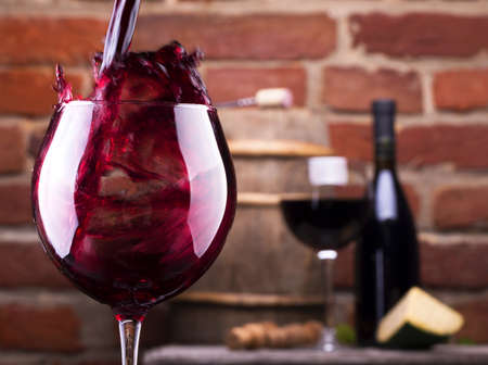Glass of wine and some fruits, bottle of wine, cheese against a brick wall.の写真素材