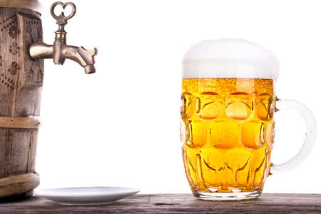 Glass of beer with barrel on a wooden table white backgroundの写真素材