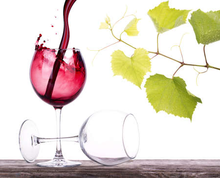 pair of full and empty wine glasses on a wooden tableの写真素材