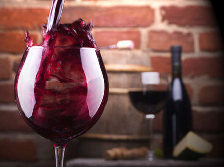 Glass of wine and some fruits, bottle of wine, cheese against a brick wall.の写真素材