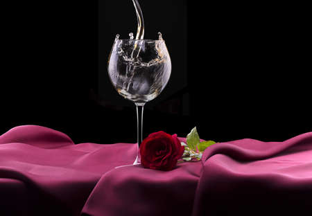 glass of wine and red rose on black backgroundの写真素材