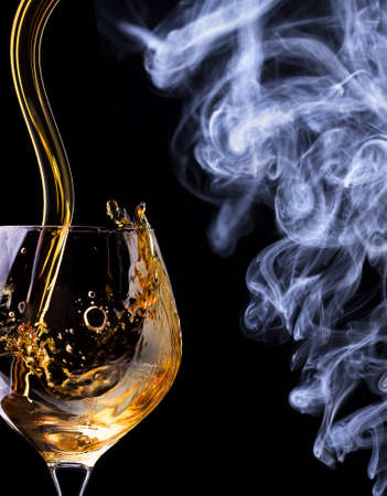 Cognac glass shrouded in a smoke on a black backgroundの写真素材