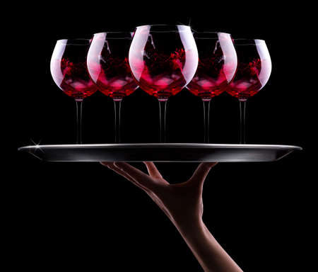waiter hand and tray with glass of red wine on a blackの写真素材