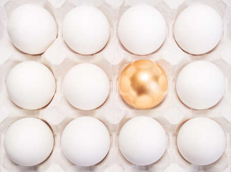 gold Easter egg between many white eggsの写真素材