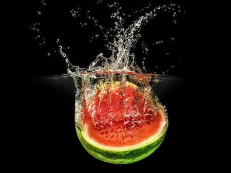 Fresh melon falling in water with splash on black background.の写真素材