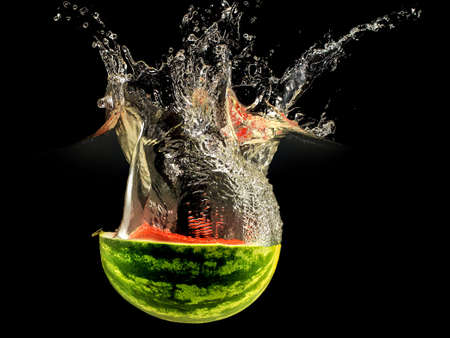 Fresh melon falling in water with splash on black background.の写真素材