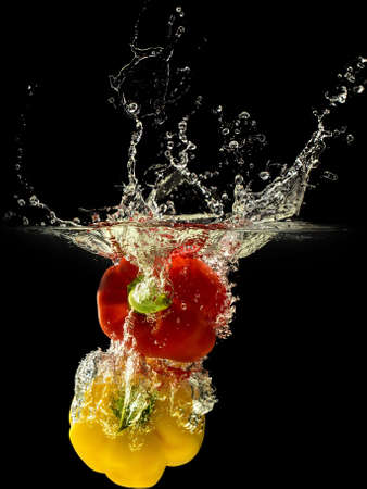 Group of bell pepper falling in water with splash on black background.の写真素材