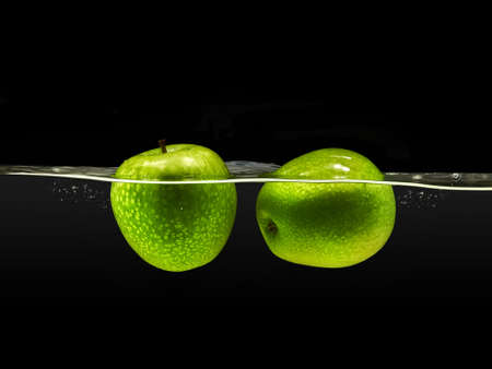 Group of green apples falling in water with splash on black background.の写真素材