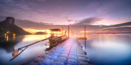 Tropical tranquil shore and pier in rays of dawnの写真素材