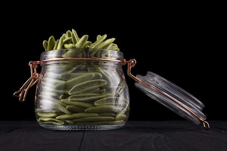 Jar of foglie spinach pasta on wooden table isolated on blackの写真素材