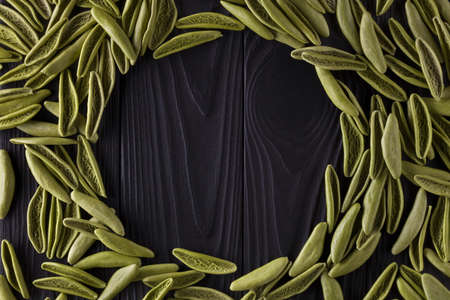 Top view of foglie spinach pasta on black wooden table with space for your text