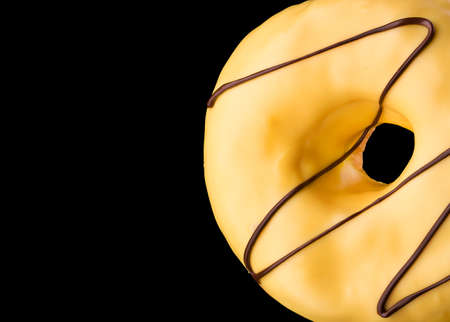 Glazed donut with sprinkles on a black backgroundの写真素材