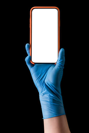 Doctors hand in medical gloves holding phone isolated on blackの写真素材